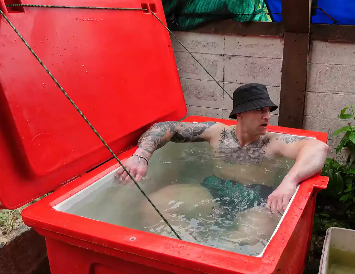 Sportif immergé jusqu’aux épaules dans un bain de glace, séance de bain froid de deux à quatre minutes