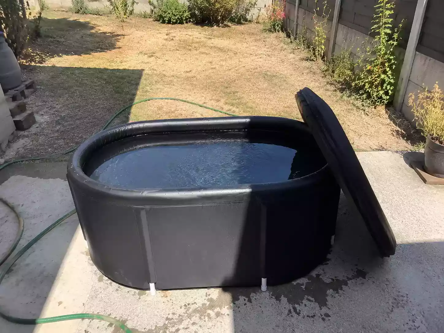 Bac de bain froid en plein soleil l’été, couvercle entrouvert, eau claire et tiède faute de refroidisseur