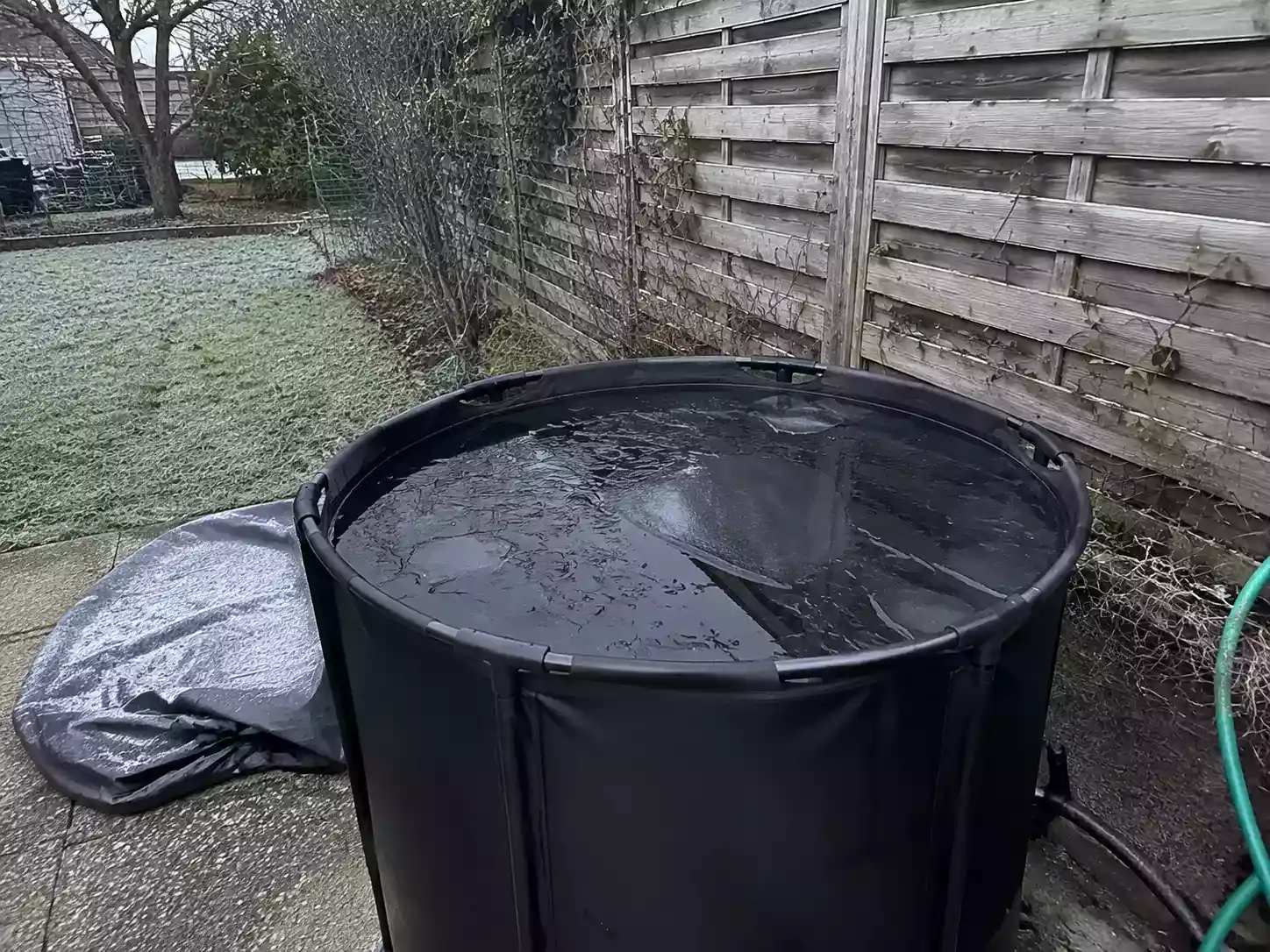 Bac de bain froid installé dehors sur une terrasse, croûte de glace brisée à la surface un matin d’hiver