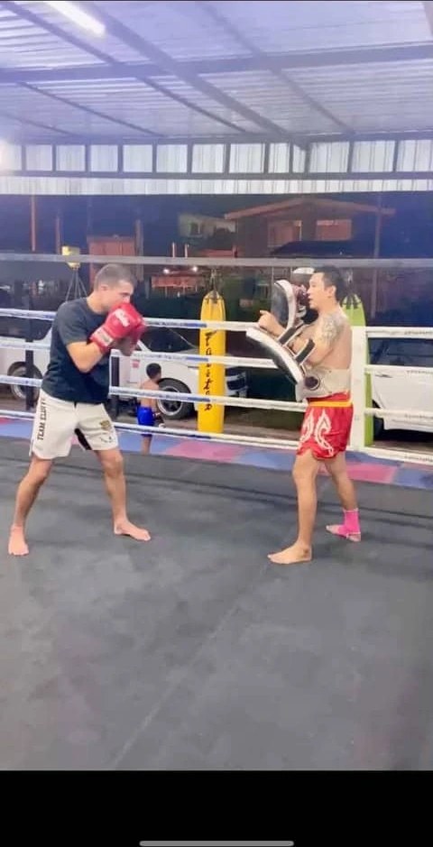 Jules Lieuron aux pattes d'ours face à un entraîneur thaïlandais dans un ring en plein air